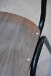 Detailaufnahme des Vintagestuhls ZERO von Jan Kurtz aus dunklem Walnussholz mit schwarzem Stahlgestell: auf der Sitzfläche ist die lebendige Maserung des Holzes deutlich sichtbar Vintagestuhl aus Stahl in schwarz und Holz in Walnuss - ZERO von Jan Kurtz