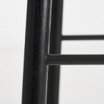 Detailansicht des Gestells des Design Tresenstuhls MONO von WOUD in Eiche, schwarz lackiert mit schwarzen Fußstützen Detail Gestell Tresenstuhl mit Lehne aus Holz in Eiche schwarz - MONO von WOUD