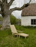 Der Liegestuhl BETWEEN LINES mit Holz-Hocker für ein entspanntes Liegen unter dem Gartenbaum Skagerak - BETWEEN LINES Liegestuhl aus Holz im Garten