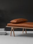 Vor einem dunklen Hintergrund heben sich die hellen Ausführungen des LEVEL DAYBED von WOUD deutlich ab  WOUD - LEVEL DAYBED Relaxliege aus Holz in Eiche und Leder cognac