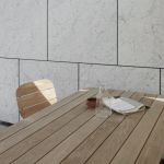 Die Oberflächen der LILIUM Serie von Skagerak by Fritz Hansen - Tischplatte, Sitz- und Rückenflächen - setzen sich aus einzelnen Teakholzlatten zusammen Skagerak LILIUM Gartenmöbelset für vier Personen mit zwei Stühlen einer Bank und einem Tisch aus Holz und Metall