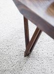 Detailansicht des Couchtisches SOFABORD von Noyer: die massive Tischplatte wird von drei kunstvoll gestalteten Tischbeinen getragen Detail Designer Couchtisch aus Holz in Nussbaum - SOFABORD von Noyer
