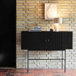 Vor einer hellen Wand setzt das Sideboard ARRAY von Woud in schwarz lackierter Eiche ein echtes Statement WOUD - ARRAY Sideboard aus Holz in Eiche schwarz mit Metallgestell (120 cm breit)